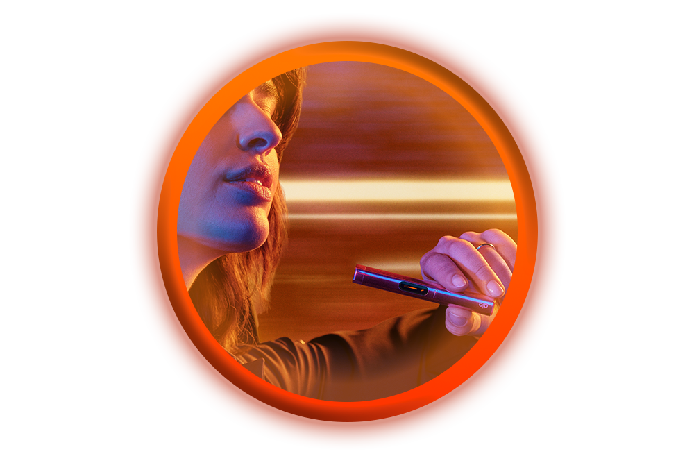 A close-up of a person holding a vape pen near their lips, surrounded by an orange glowing circular border with warm, colorful lighting in the background.