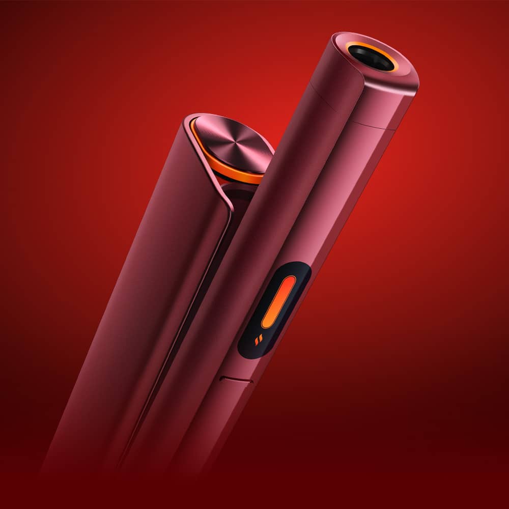Close-up of two sleek, red and orange stylus pens or electronic devices standing upright against a red gradient background, highlighting their modern design and button details.