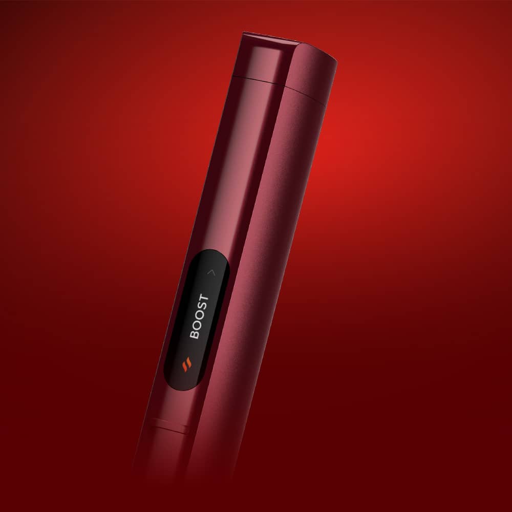 A close-up of a sleek, cylindrical red electronic device with a black display showing the word BOOST against a red gradient background.