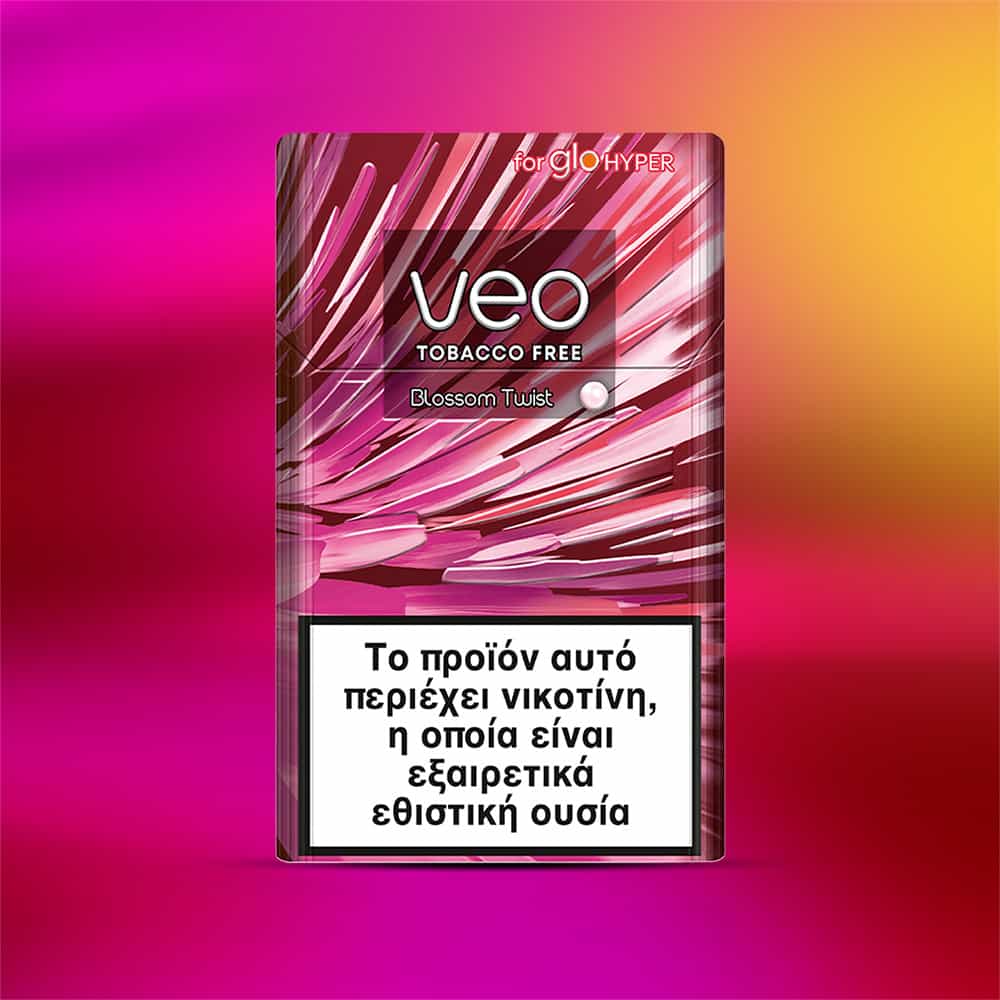 A rectangular veo™ Blossom Twist package with abstract pink and white designs features Greek nicotine warnings on the front. Its background displays a gradient of pink, purple, and yellow shades.