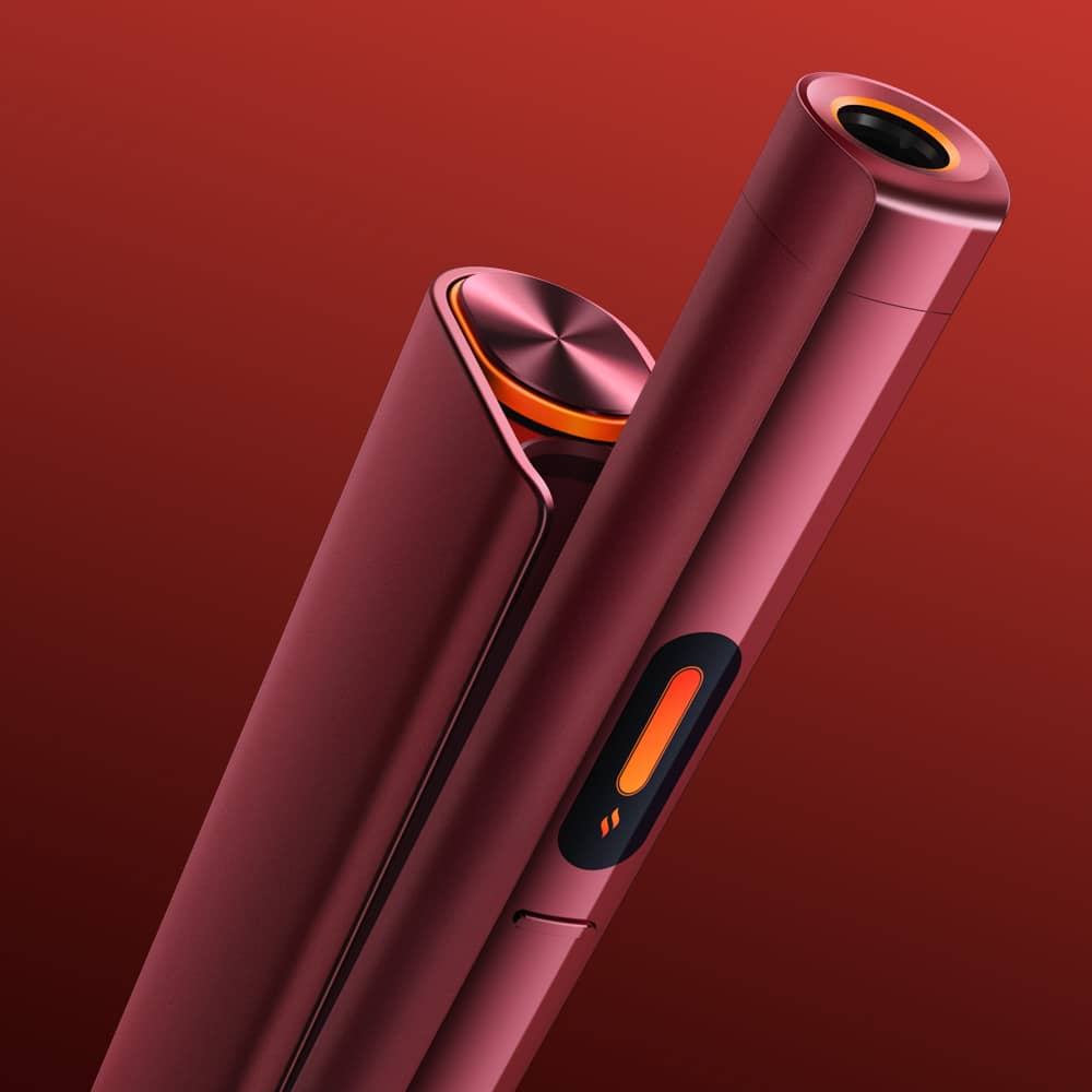 A close-up of two sleek glo™ HILO Plus devices in metallic red with orange accents, featuring cylindrical shapes and a button marked with a flame icon, set against a gradient red background.