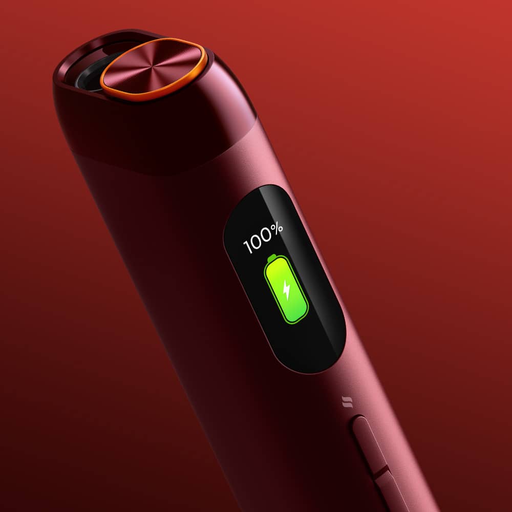 A close-up of the sleek, red glo™ HILO device with a digital display showing 100% battery and a green icon, set against a gradient red background.