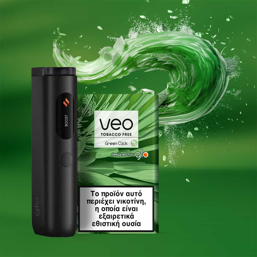 A black electronic device stands next to a veo™ Green Click tobacco-free pack with Greek text and a swirling green abstract background. The pack warns in Greek that the product contains nicotine, an addictive substance.