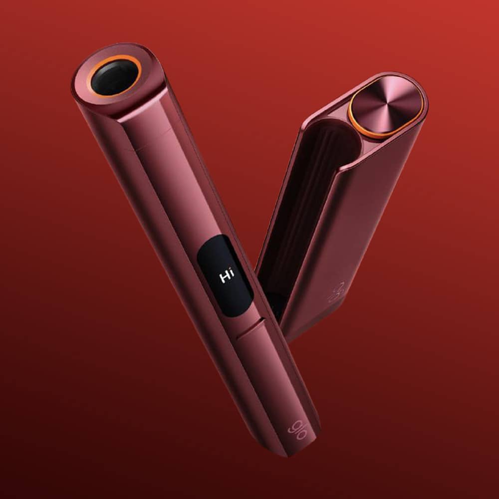 Two sleek, metallic red glo™ HILO Plus devices with rounded edges sit against a gradient red background. One shows "Hi" on its small screen, and both have circular openings at the top.
