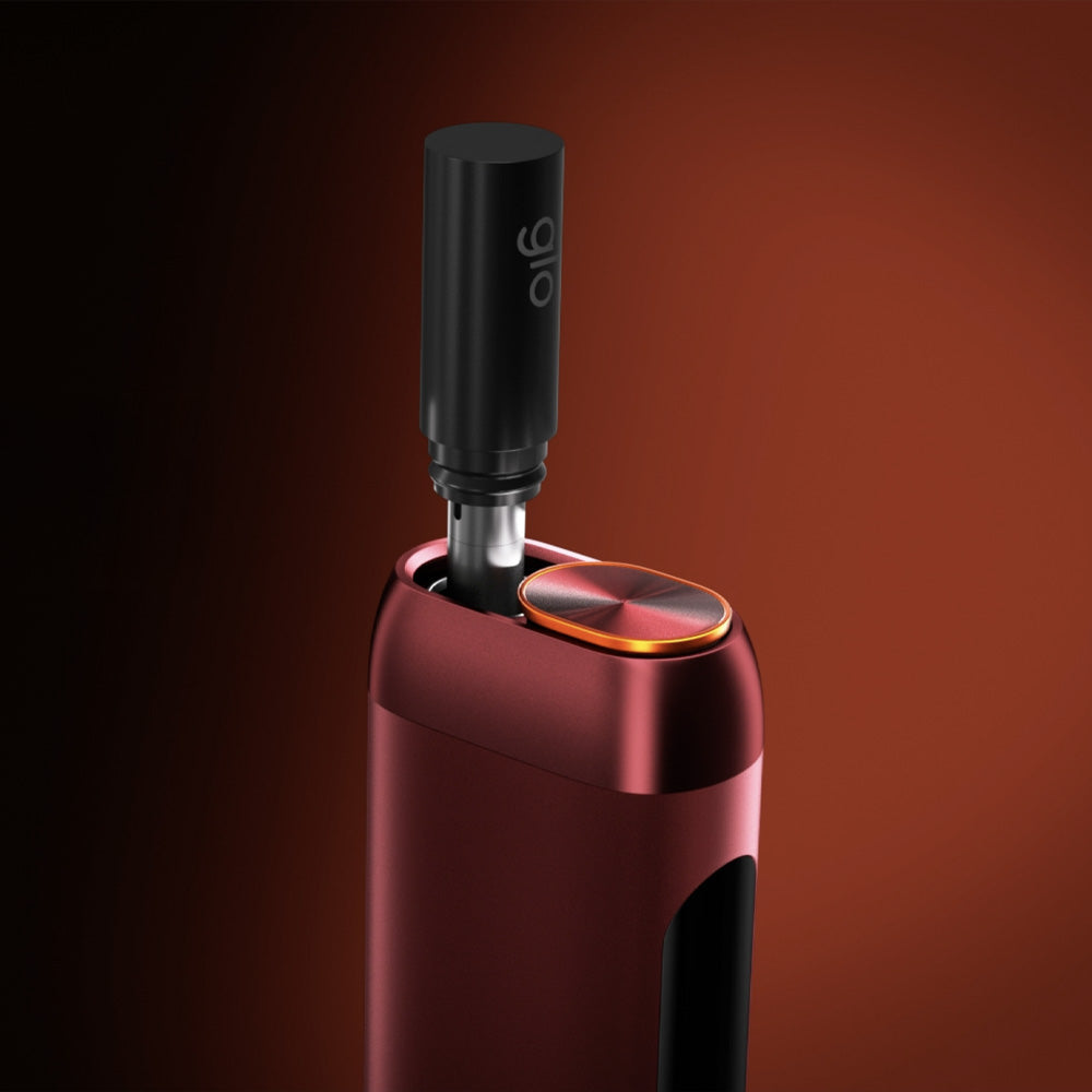 A close-up of the sleek, metallic red glo™ HILO Stick Remover with a black cylindrical attachment, set against a gradient dark red background. An illuminated button appears near its heating chamber.