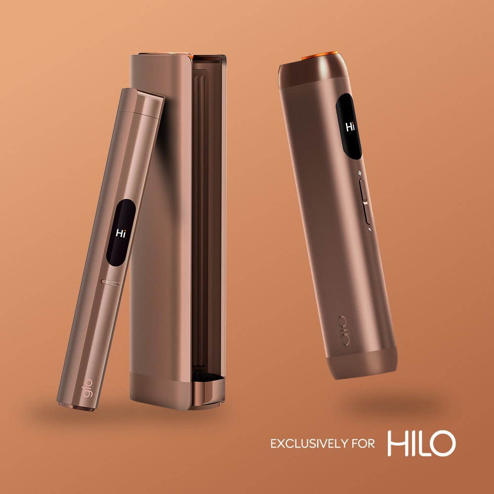 Two sleek virto™ Silver Tobacco devices with display screens are shown—one in a charging case, one standing upright. Text reads EXCLUSIVELY FOR HILO on a light brown background.