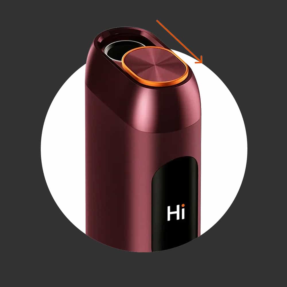 A maroon electronic device with a large circular gold button on top, a digital display showing Hi, and an orange arrow pointing to the button, all set against a dark background.