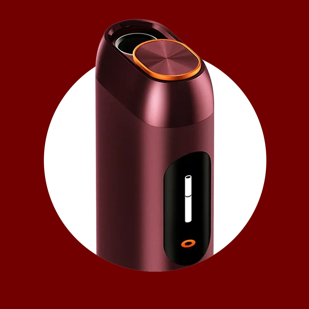 A sleek, maroon electronic device with a circular orange-rimmed button on top and a small display screen showing a white bar and orange circle, set against a white circle on a dark red background.