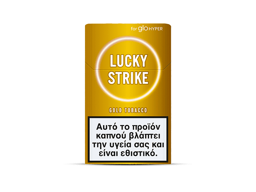 A yellow and gold pack of Lucky Strike Gold Tobacco cigarettes displays a Greek health warning label about the harmful and addictive effects of smoking. The tobacco offers nutty and creamy flavor notes.