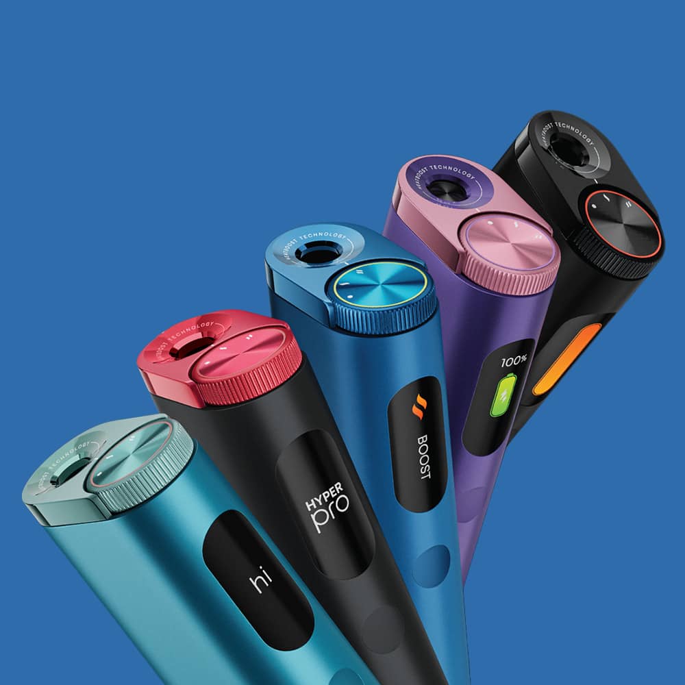 Five colorful electric toothbrush handles, each in different shades (turquoise, red, blue, purple, and black), stand upright against a blue background, showing various buttons and design details.