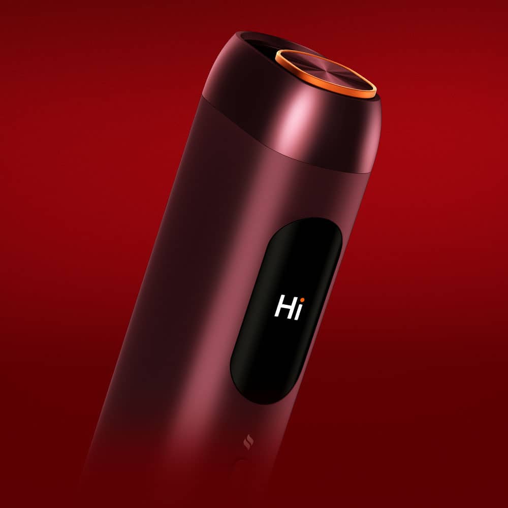 A sleek, cylindrical electronic device with a dark red finish displays the word Hi on its screen, set against a deep red background. The top edge has an illuminated circular rim.