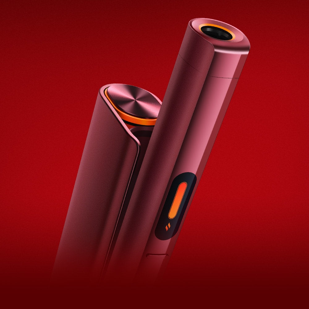 Two sleek, red electronic devices with metallic accents and rounded edges, standing upright against a red background. One device has an orange circular button and a black oval opening at the top.